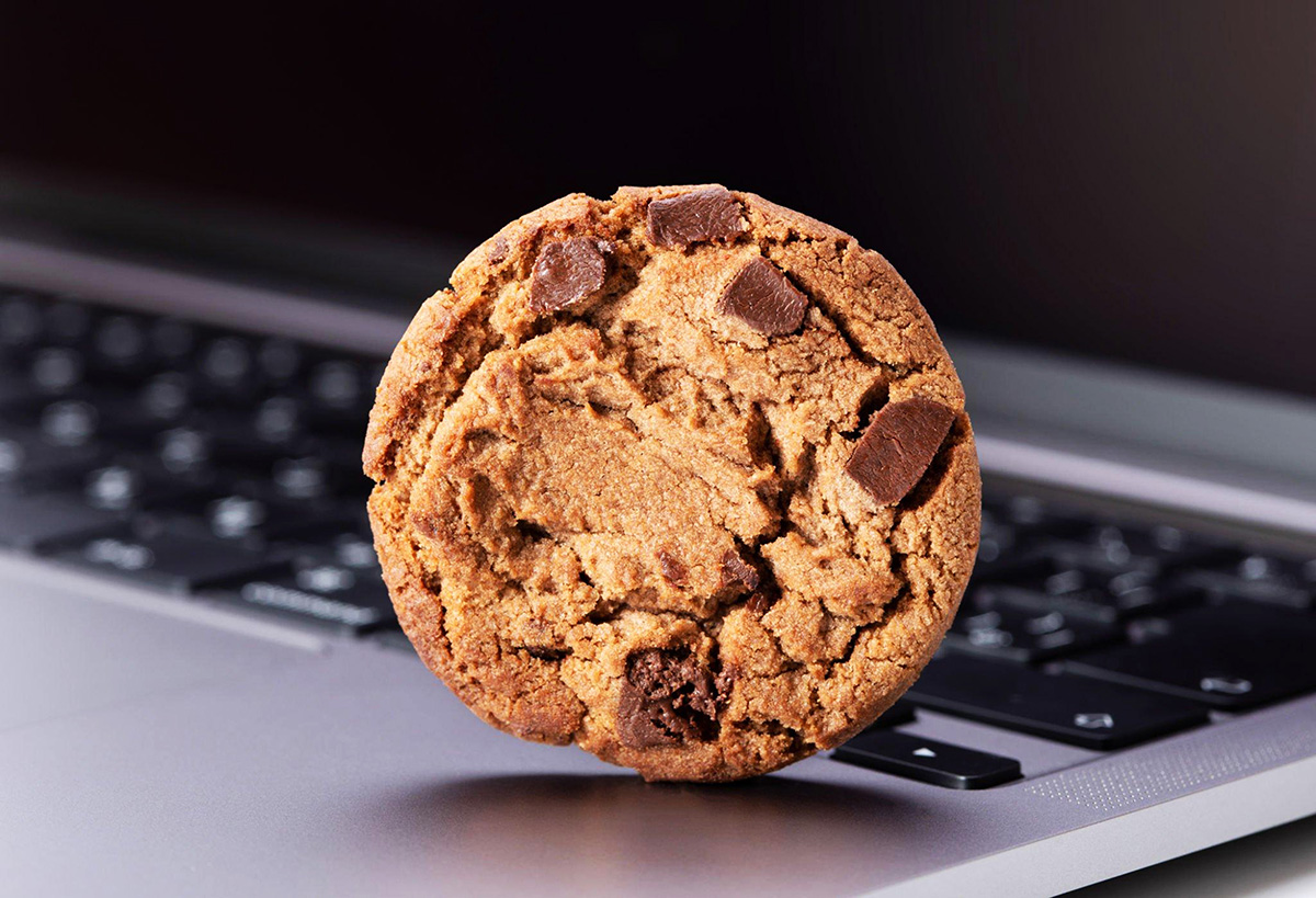 Milk chocolate chip cookies resting on top of a laptop keyboard